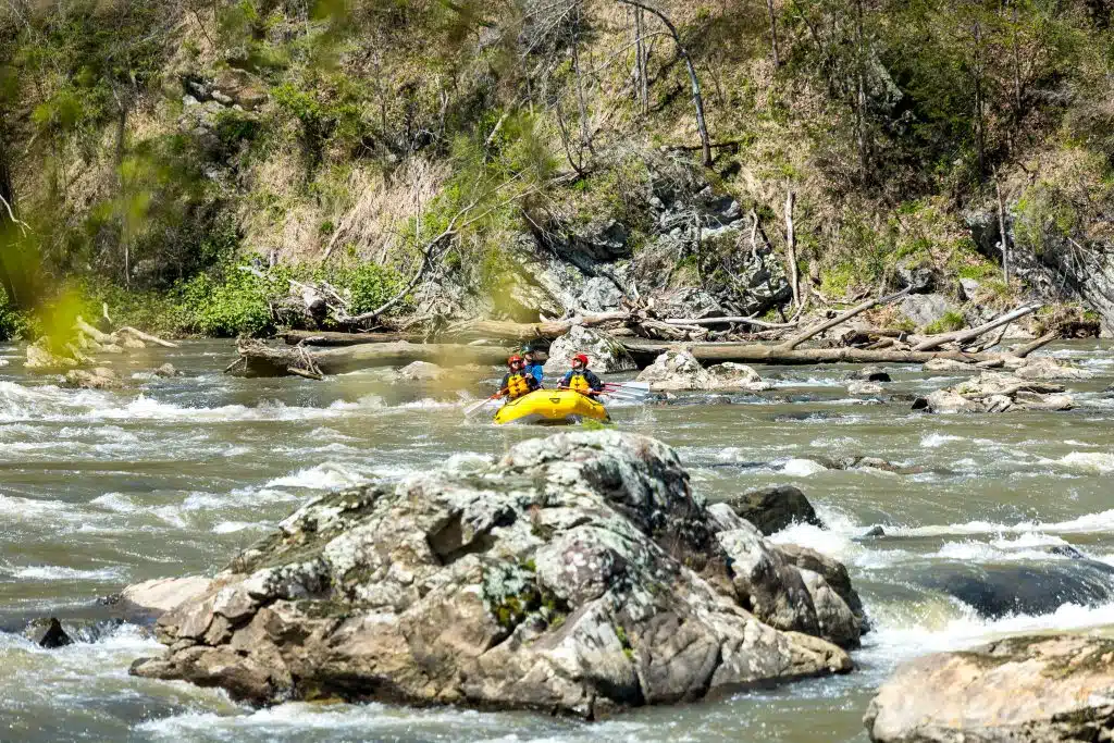 French Broad Section 9 Rafters enjoying a warm sunny day in the blue ridge mountain rafting down the French Broad in life jackets and helmets.