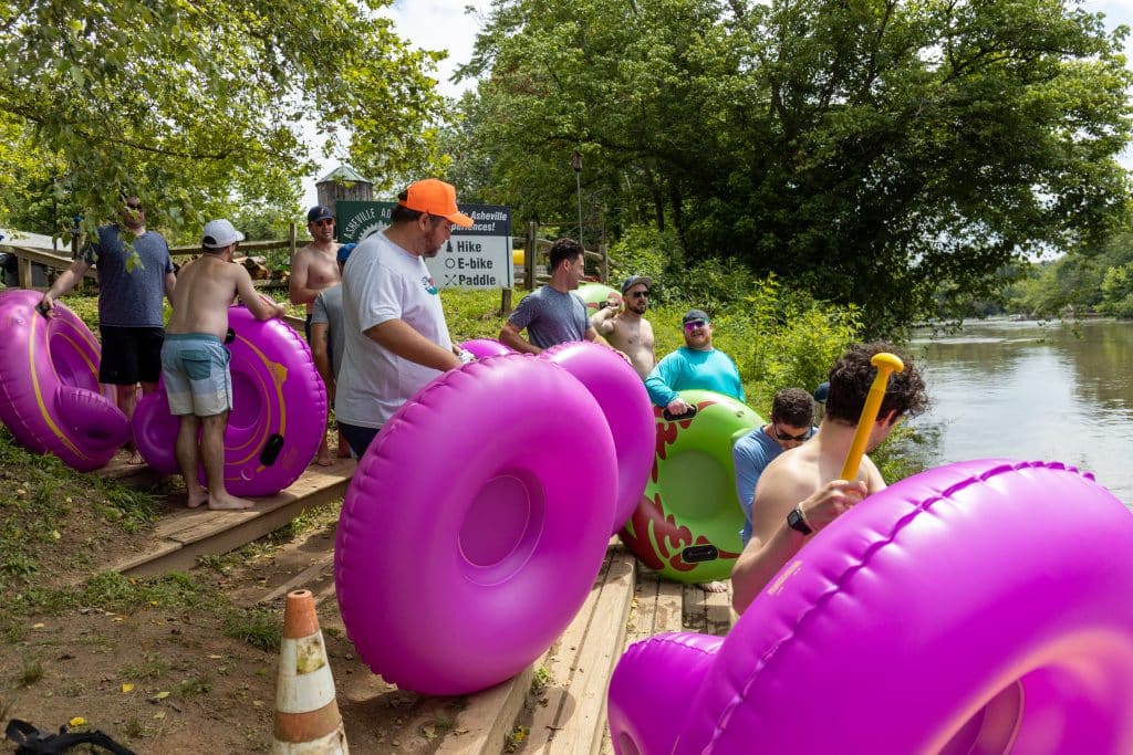 Standing on Asheville Adventure Company's dock with inner tubes in hand getting ready to float down the lazy river to the river arts district.